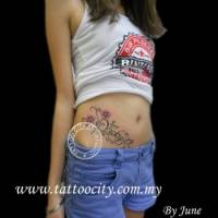 Tatuaje de unas flores y un nombre en la barriga de una chica