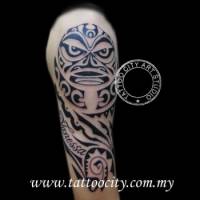 Tatuaje de una cara maorí en el brazo con un nombre