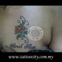 Tatuaje de una flor y un texto encima del pecho de una mujer