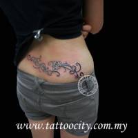 Tatuaje de un tribal con flores encima del culo de una chica