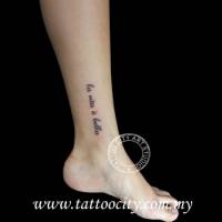 Tatuaje de la frase la vita e bella en el tobillo de una mujer