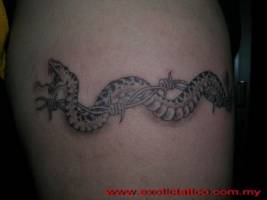 Tatuaje de una serpiente entre un alambre de espinos