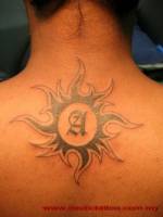 Tatuaje de un sol en la nuca con una inicial