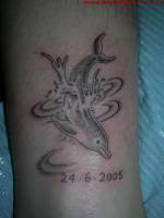 Tatuaje de un delfín sumergiéndose en el agua con una fecha