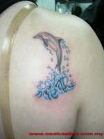 Tatuaje de un delfín saliendo del agua en la espalda de una mujer