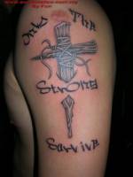 Tatuaje de una cruz afilada atravesando la piel y una frase