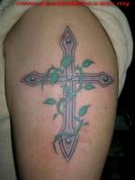 Tatuaje de una cruz metálica en el brazo, con una enredadera espinada
