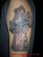 Tatuaje de una cruz con un murciélago saliendo de ella