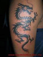 Tattoo en el brazo de un dragón  hecho con tribales