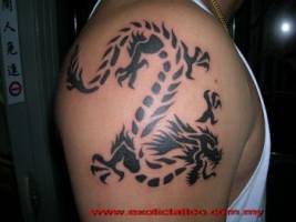 Tatuaje de un dragon en el hombro. El dragón hecho de tribales