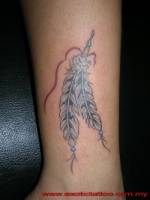 Tatuaje de un par de plumas indias en la pierna