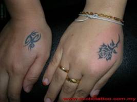Tatuaje de un tribal en una mano y una rosa en la otra