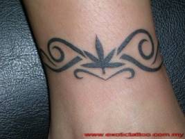 Tatuaje de un brazalete tribal con una hoja enmedio
