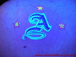 Tatuaje ultravioleta de una inicial con 3 estrellas