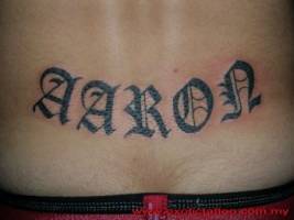 Tatuaje de el nombre Aaron con letras góticas encima del culo