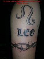 Tatuaje de un nombre entre un brazalete de espinas y un símbolo onduload
