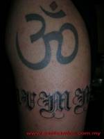 Tatuaje del simbolo om en el brazo con un nombre de brazalete