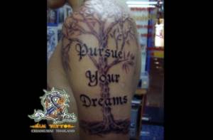 Tatuaje de un árbol en el brazo y una frase