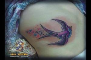 Tatuaje de una golondrina con una estela de estrellas