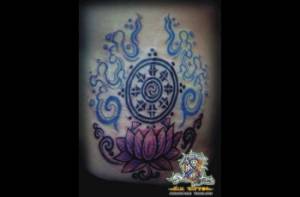Tatuaje de una flor de loto con el símbolo de la rueda de  ocho radios budista