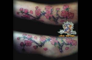 Tatuaje de una rama de árbol con flores, en el pie