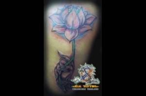 Tatuaje de una mano sujetando una flor de loto