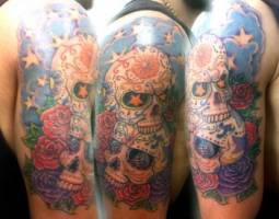Tatuaje en color de dos calaveras mexicanas, con estrellas, diamantes y nubes