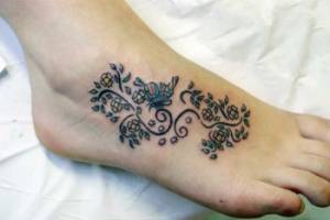 Tattoo en color de unas plantas y flores en el pie