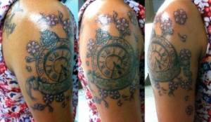 Tatuaje en color de un reloj en el brazo con unas pequeñas flores