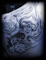 Tatuaje de una calavera con forma de pica, unos dados y una rosa