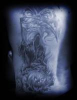 Tatuaje de la muerte con una calabaza de halloween y un espíritu chillando detrás