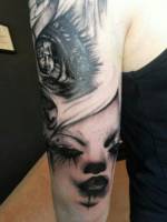 Tatuaje de un gran ojo y una cara en el brazo
