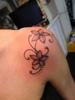 Tatuaje de unas flores en color en el hombro de una chica