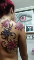 Tatuaje de grandes flores y estrellas en la espalda de una mujer