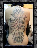 Tatuaje en la espalda entera de una chica de flores de loto en el agua y una frase