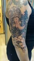 Tatuaje en el brazo de Ganesha con un edificio detrás