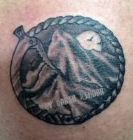 tatuaje de un circulo hecho con un un piolet y una montaña dentro
