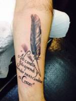 Tatuaje de una frase con una pluma en el antebrazo