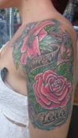 Tatuaje a color de varias flores y cintas con nombres
