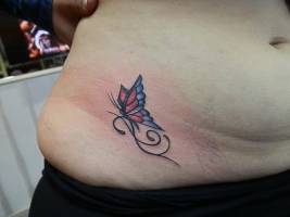 Tatuaje de une pequeña mariposa en la barriga