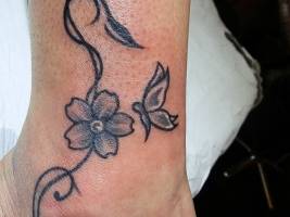 Tatuaje de una pequeña mariposa que va a una flor