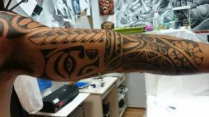 Tatuaje maori en el brazo, con una cara dentro