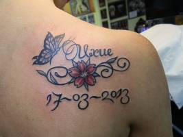 Tatuaje del nombre Uxue, con una flor, una mariposa y una fecha
