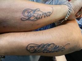 Tatuaje de un par de nombres en el antebrazo