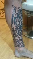 Tatuaje de una mascara y una tortuga maori en la pierna