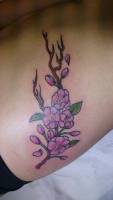 Tatuaje a color de una rama con flores