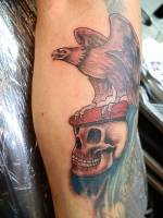 Tatuaje old school de un águila posada en una calavera
