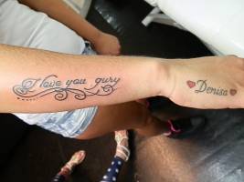Tattoo de una frase en el antebrazo y un nombre con corazones en el brazo