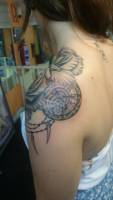 Tattoo de un reloj detrás de unas rosas  en el hombro de una mujer