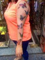 Tattoo de grandes mariposas a color  en el brazo de una mujer
